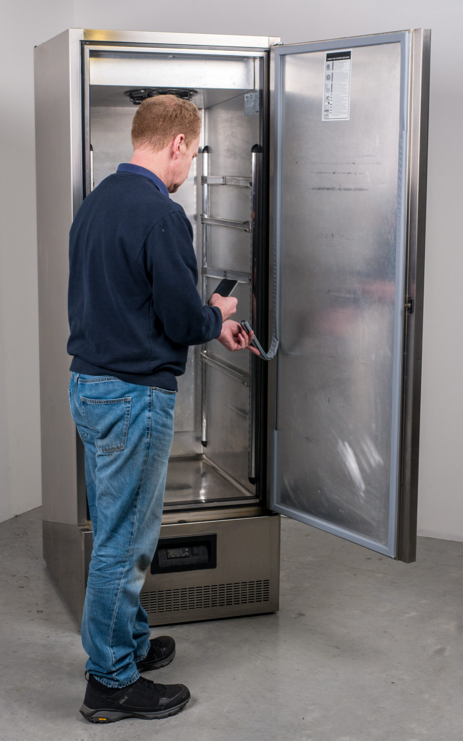 Man changing fridge seals in a commercial kitchen 