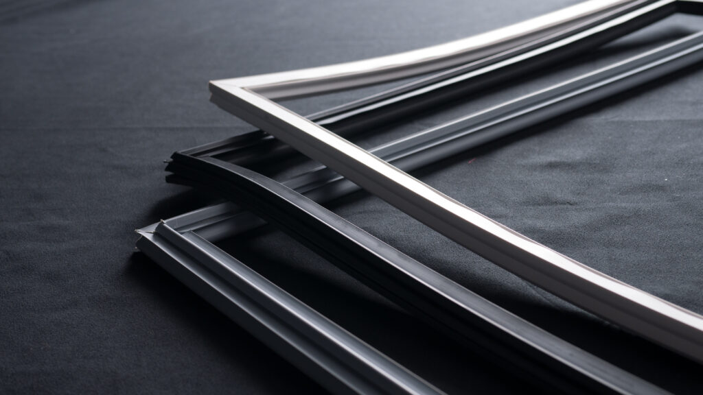 Several empty, overlapping rectangular picture frames, mostly black with one white frame, are placed on a black surface. The frames are positioned at an angle, creating strong shadows and a minimalist, modern composition.